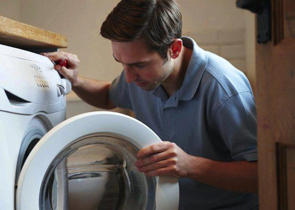 Professional engineer installing a washing machine under a countertop — washing machine installation across Tyne & Wear, Northumberland and County Durham